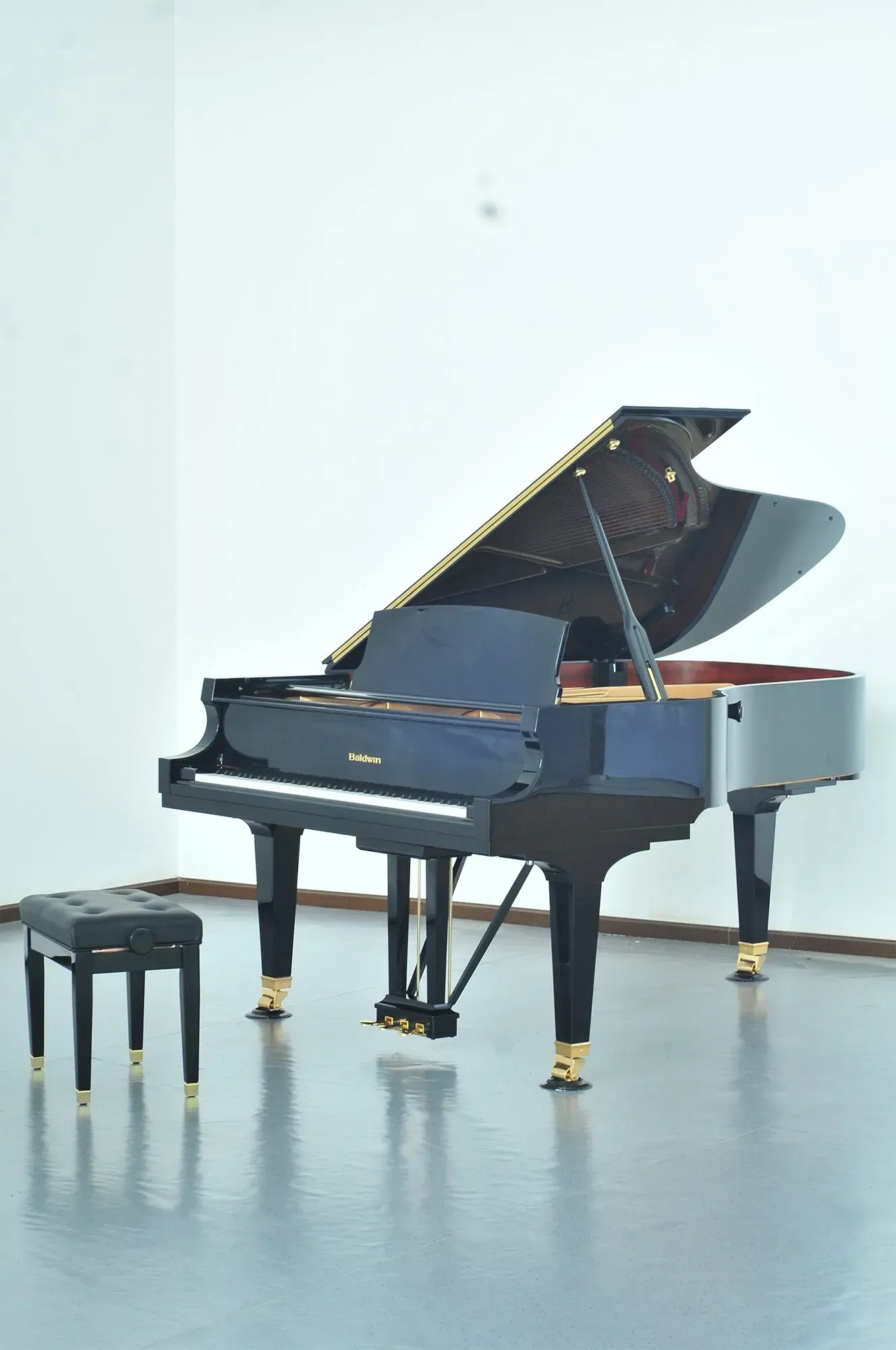 A piano is sitting in a room with the lid open and a stool next to it.