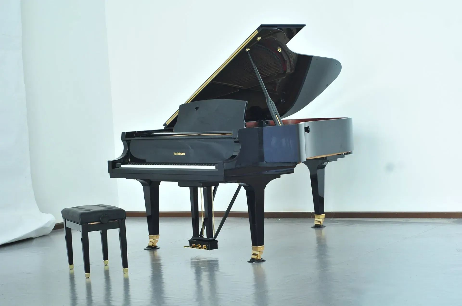 A grand piano is sitting in a room with a stool next to it.