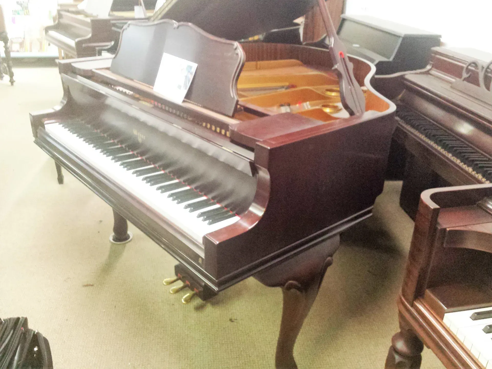 A piano is sitting in a room with other pianos