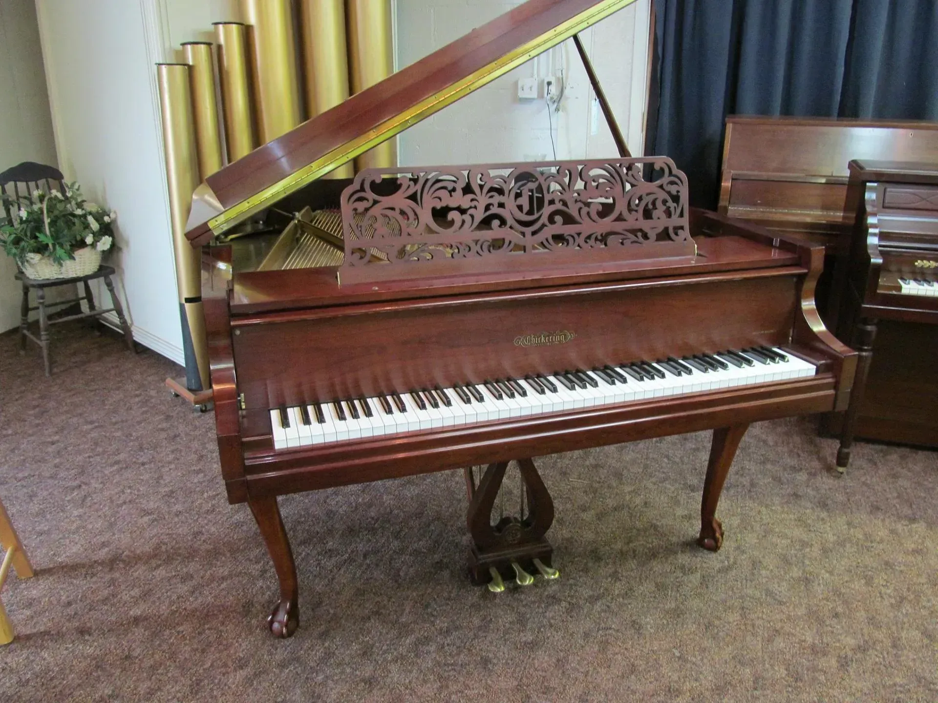 A grand piano is sitting on a carpeted floor in a room.