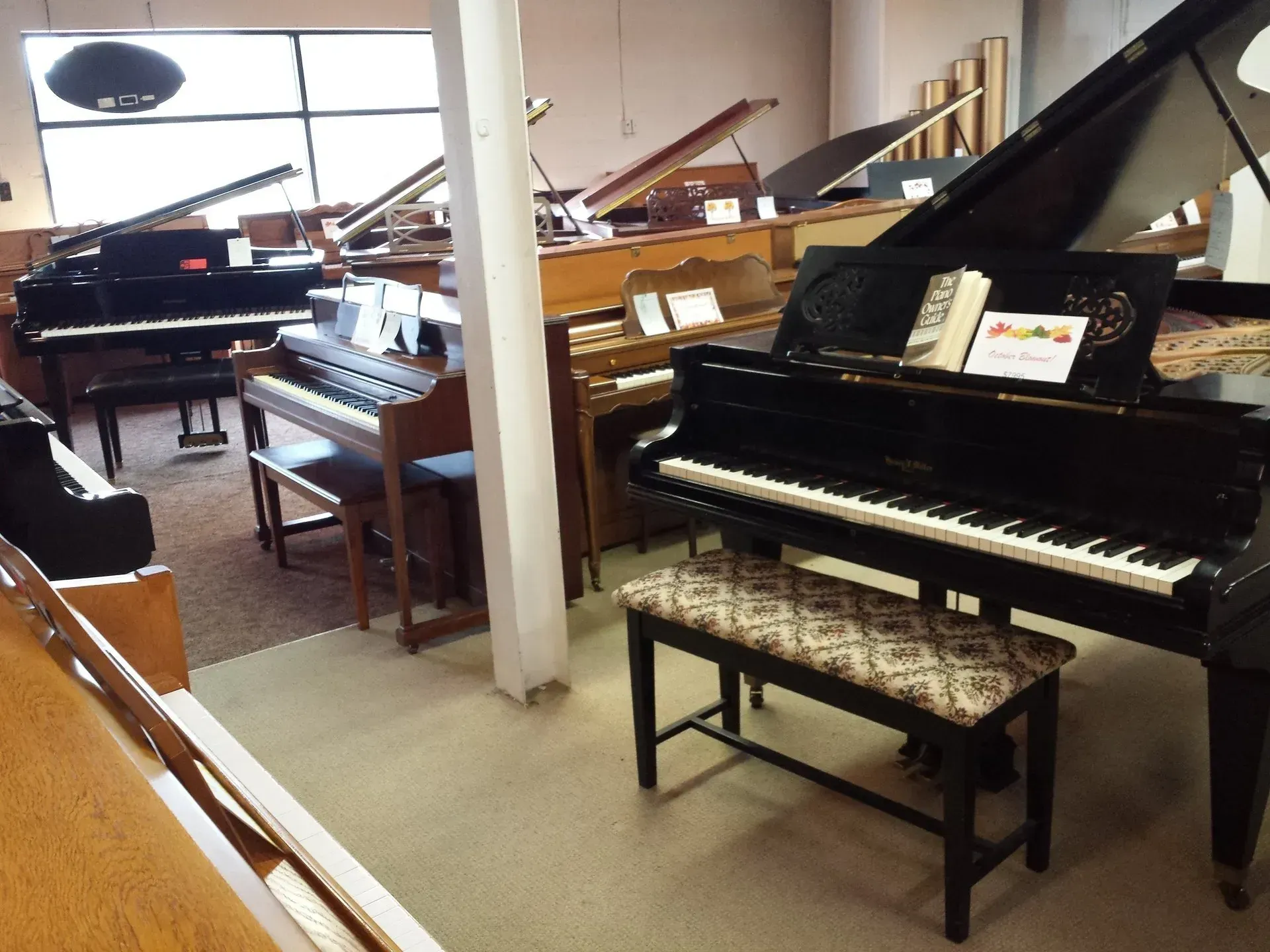 A room full of pianos including a grand piano