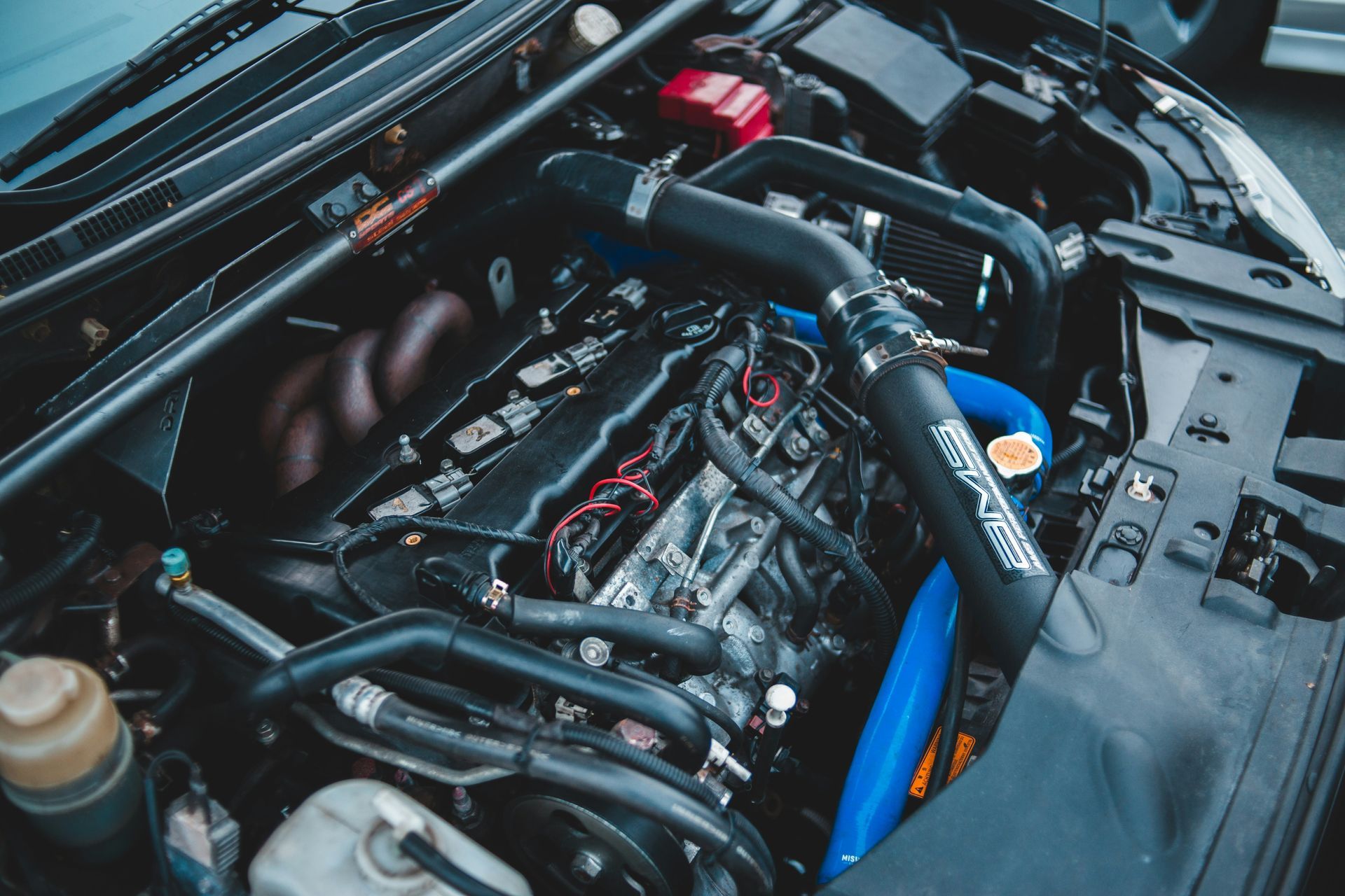 A close up of the engine of a car with the hood open.