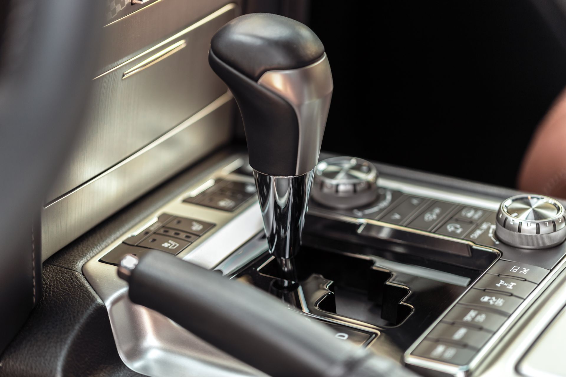 Close-up of a car’s automatic gear shift and center console with metallic controls