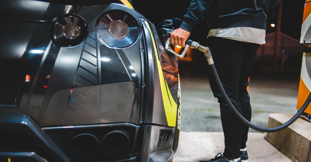 A man is pumping gas into a car at a gas station.