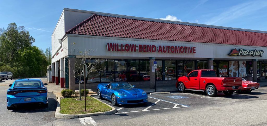 two cars are parked in front of a willow bend automotive store