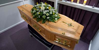 A coffin decorated with flowers awaits collection from the undertakers