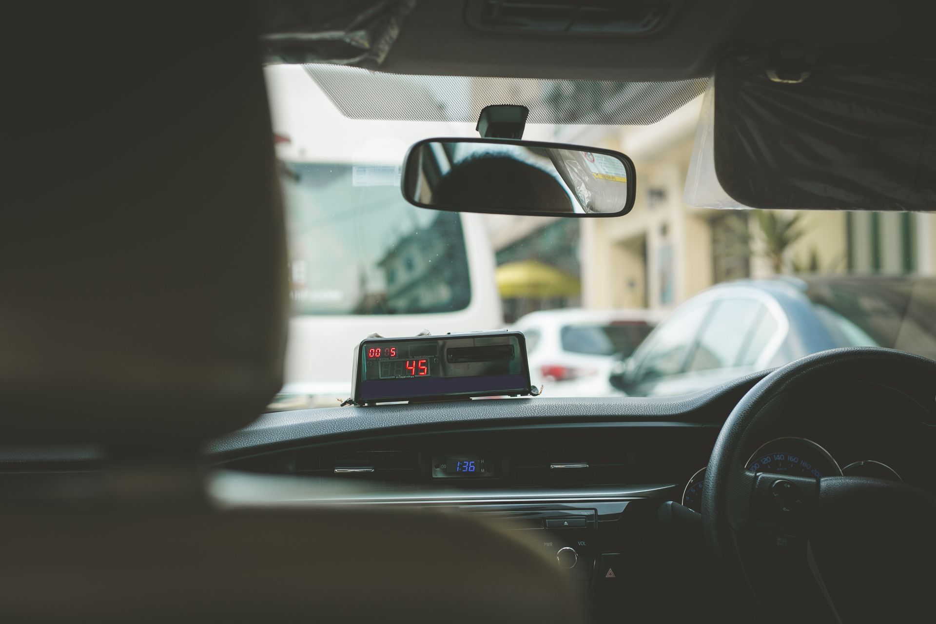 The inside of a car with a taxi meter on the dashboard.