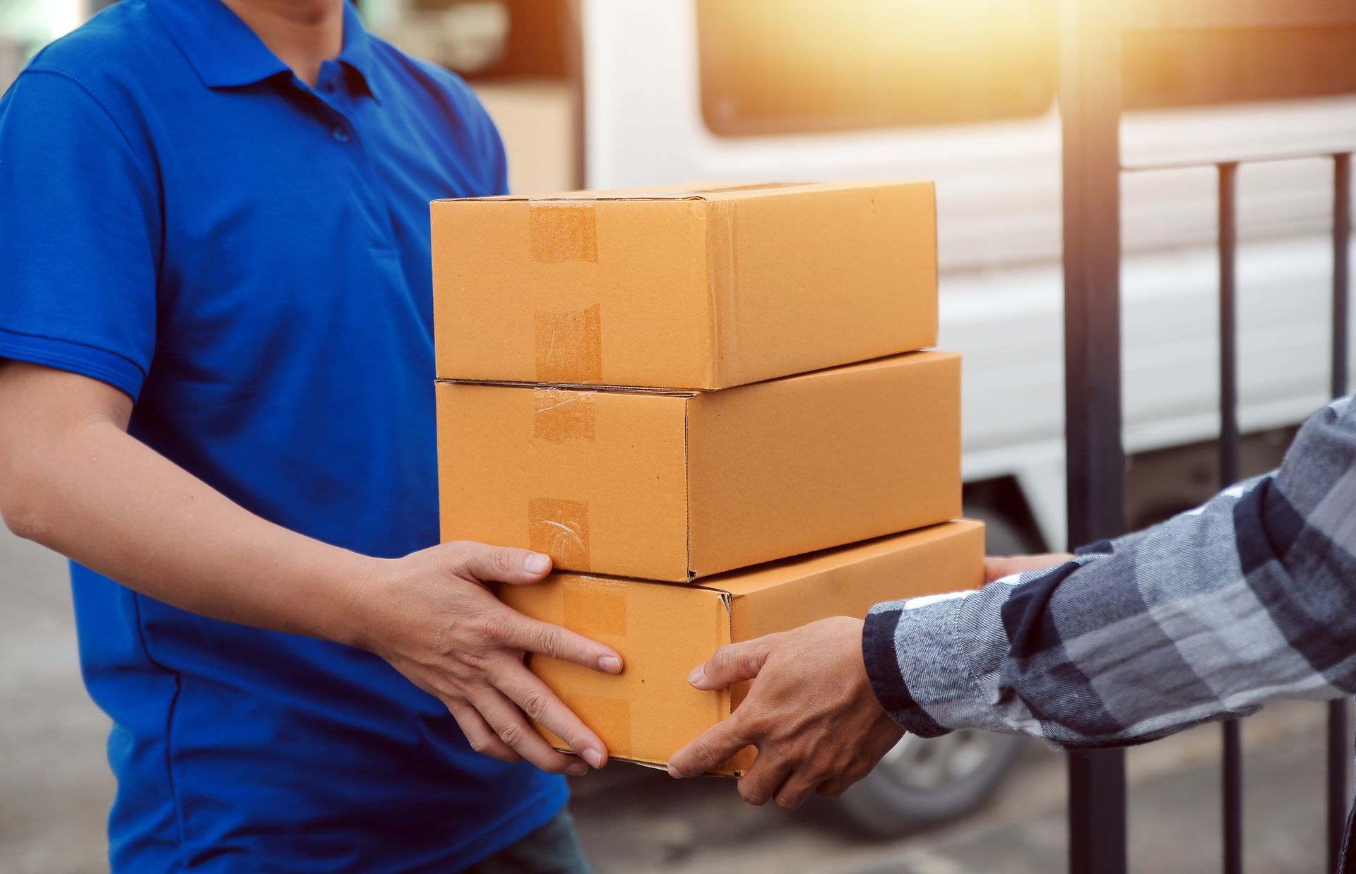 A delivery man is handing a stack of boxes to a customer.