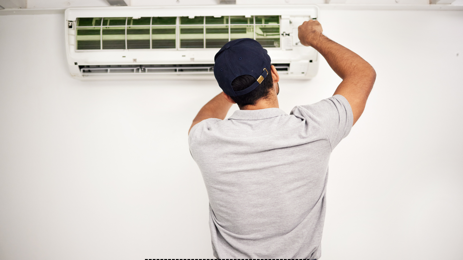 A man is fixing an air conditioner on the wall.