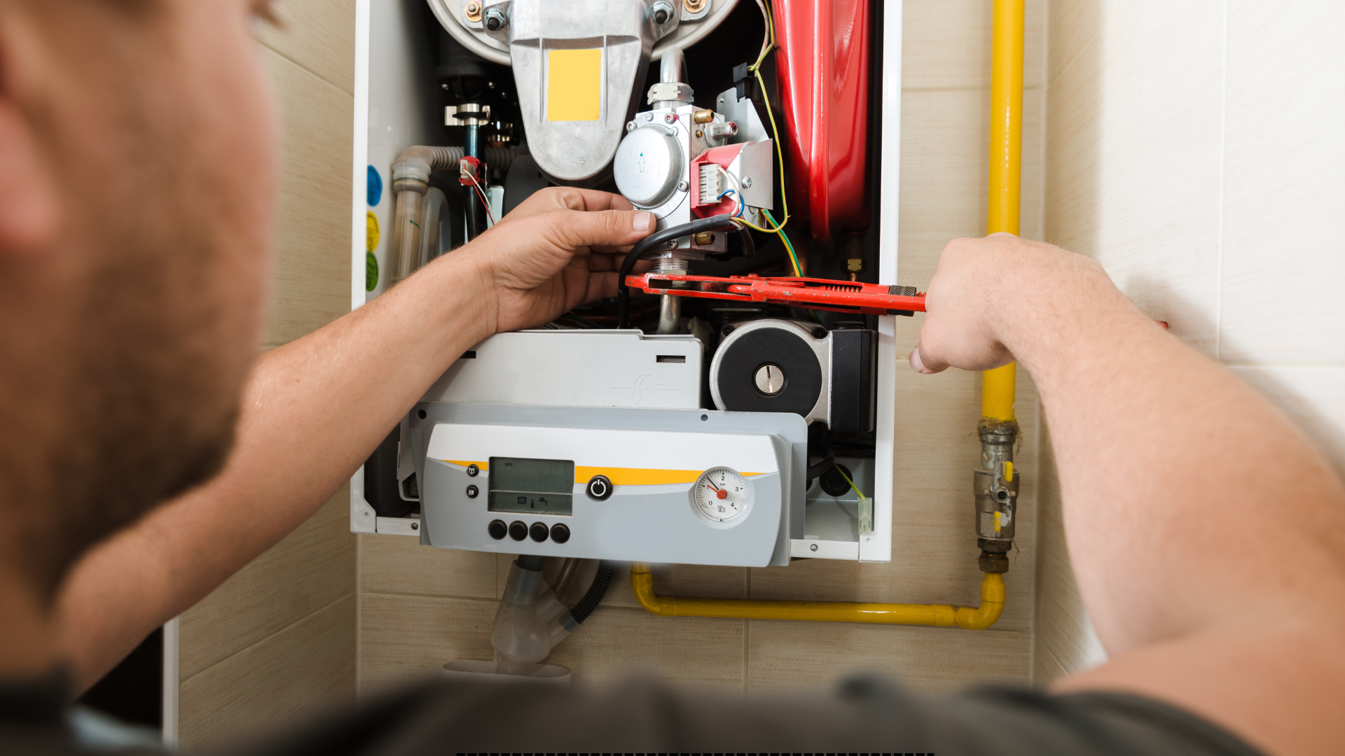 A man is fixing a boiler with a wrench.