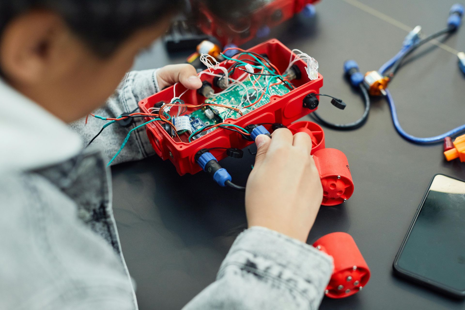 A young boy is working on a robot on a table.