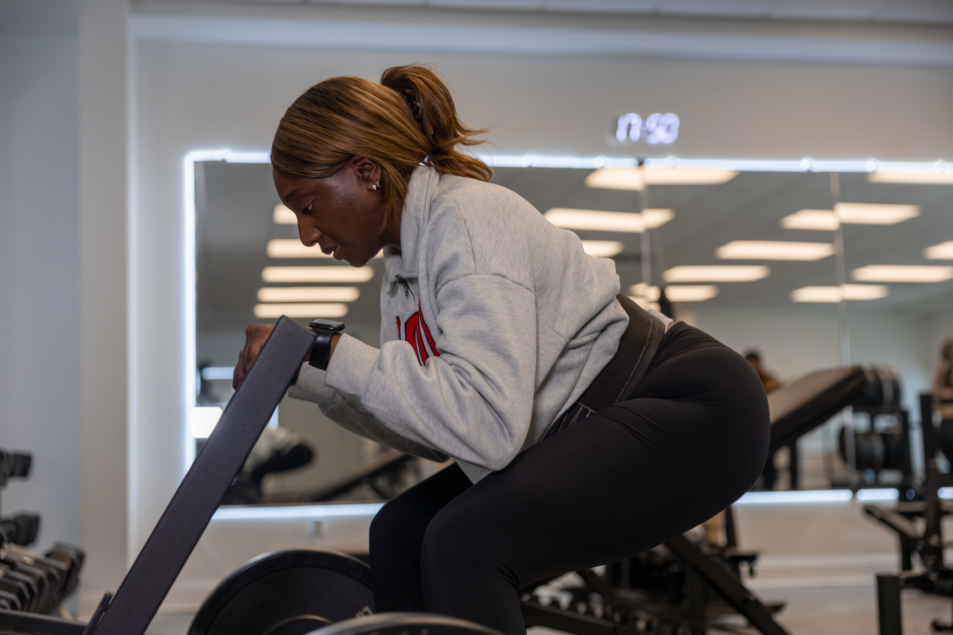 360 image fitness personal training female in sweater client doing squat and leg strength exercises wearing gym clothes