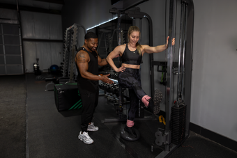Trey Johnson at 360 Image Fitness gym in Watkinsville, GA helping female client with leg strengthening with gym equipment
