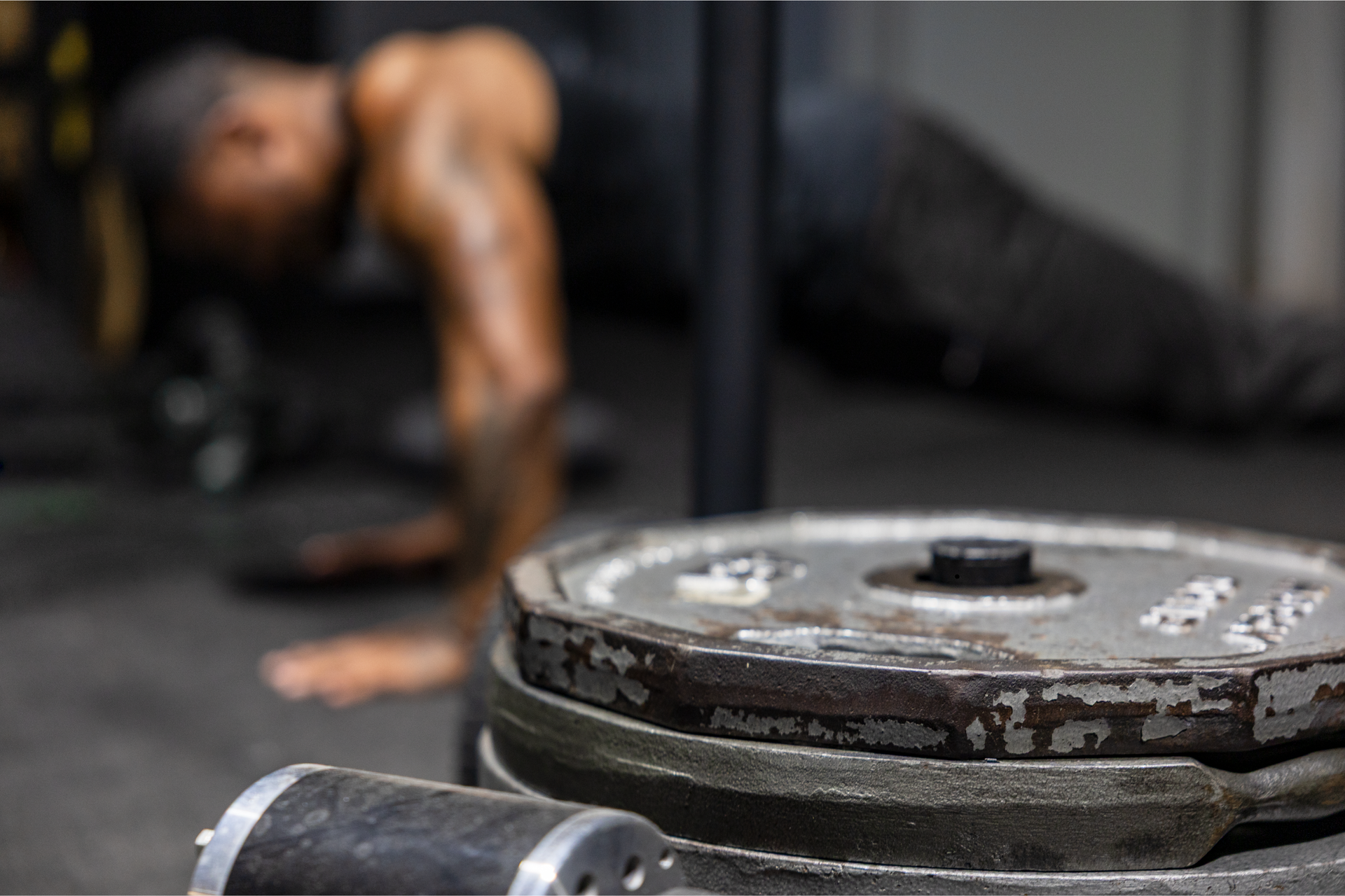 Trey Johnson at 360 image fitness doing pushups to build strength and muscle in all black workout clothes with grey weights