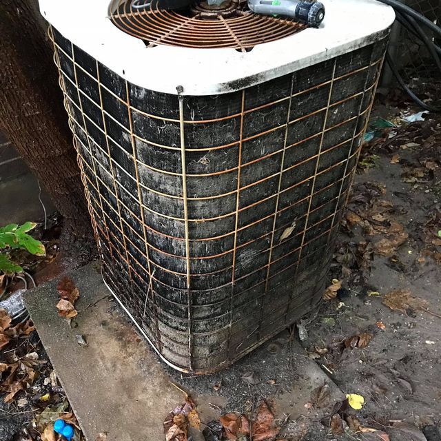 A dirty air conditioner is sitting on the ground