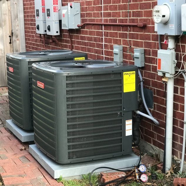 Two air conditioners are sitting outside of a brick building
