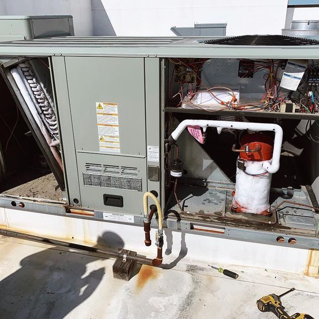 An air conditioner is being repaired on the roof of a building.