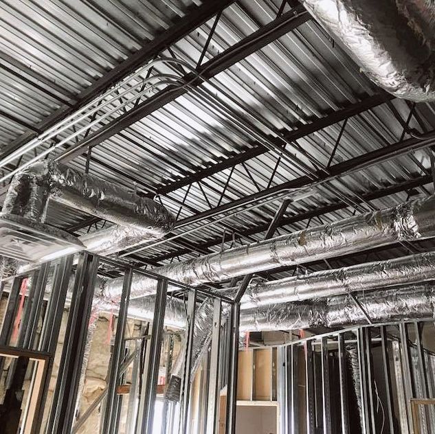 A building under construction with a lot of aircon pipes coming out of the ceiling.