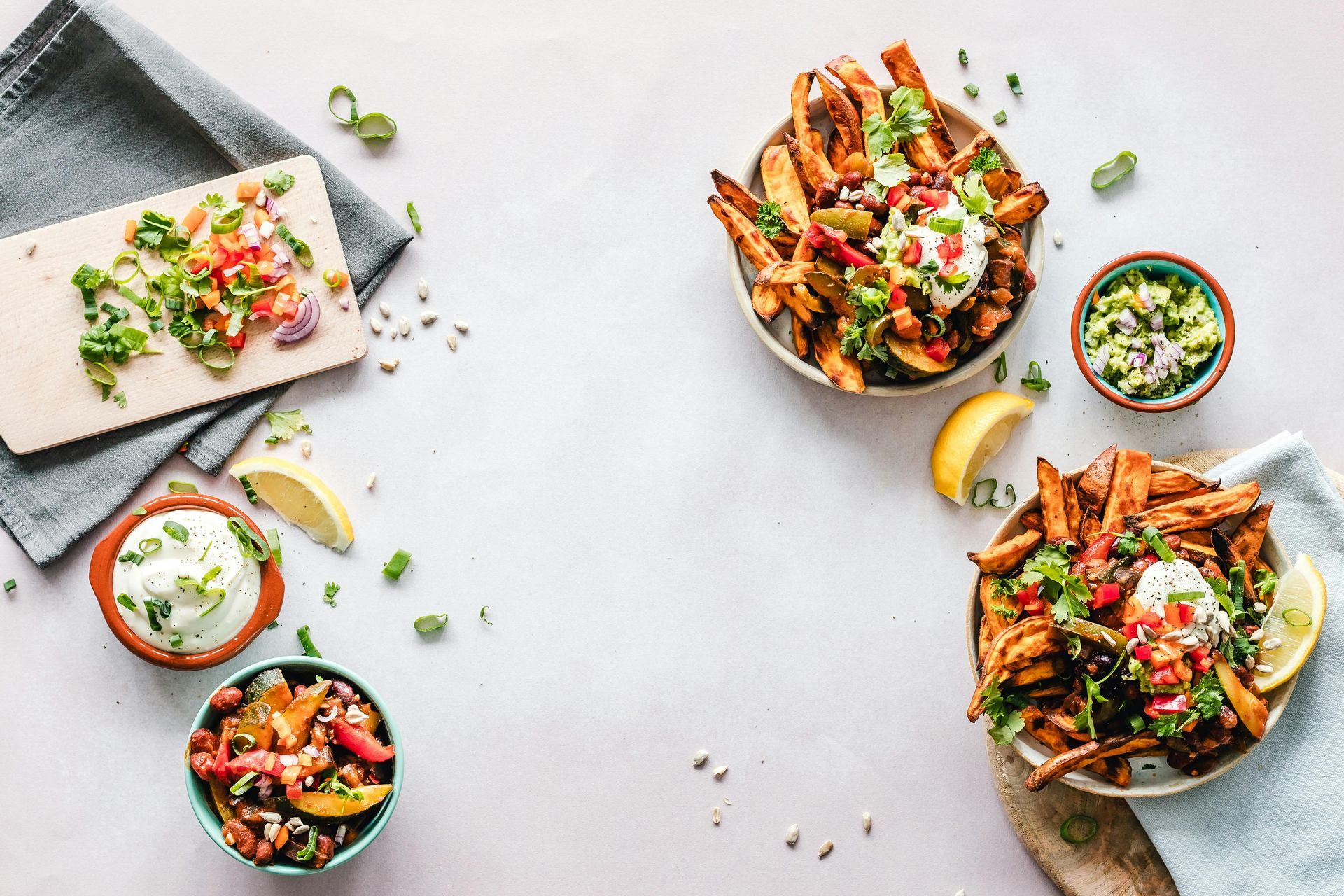 Overhead spread of colorful taco bowls, garnished tortillas, and lime on a light table
