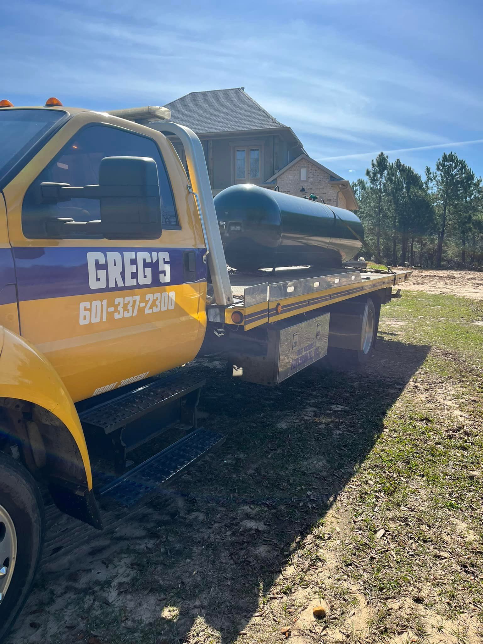 Greg's Tow Bizz truck hauling large cyllinder