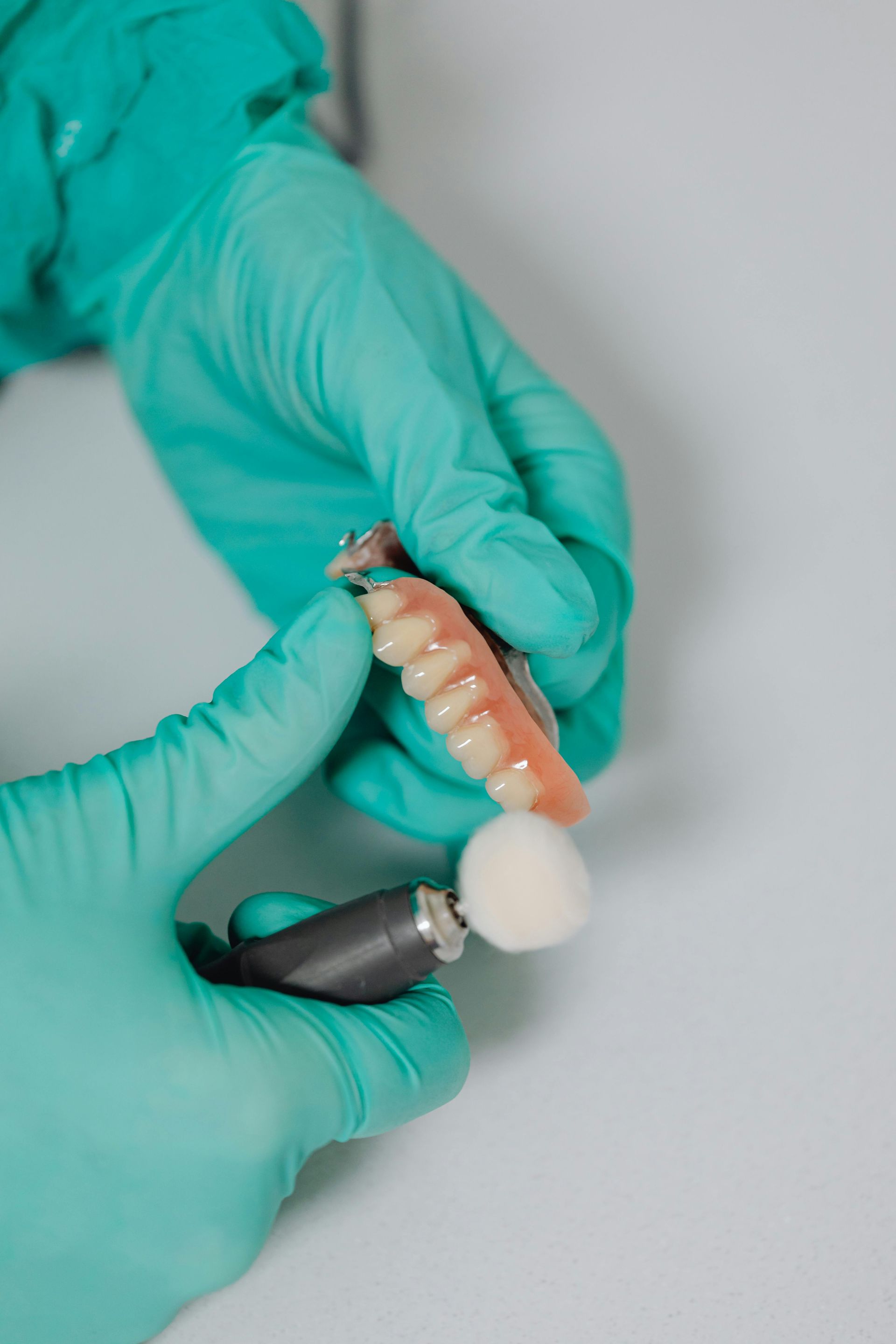 A dentist is polishing a denture with a brush.