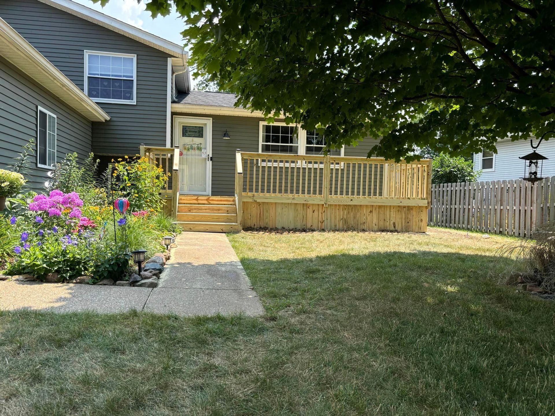 A house with a wooden deck and a fence in front of it.