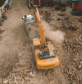 An aerial view of a construction site with a yellow excavator and a truck.