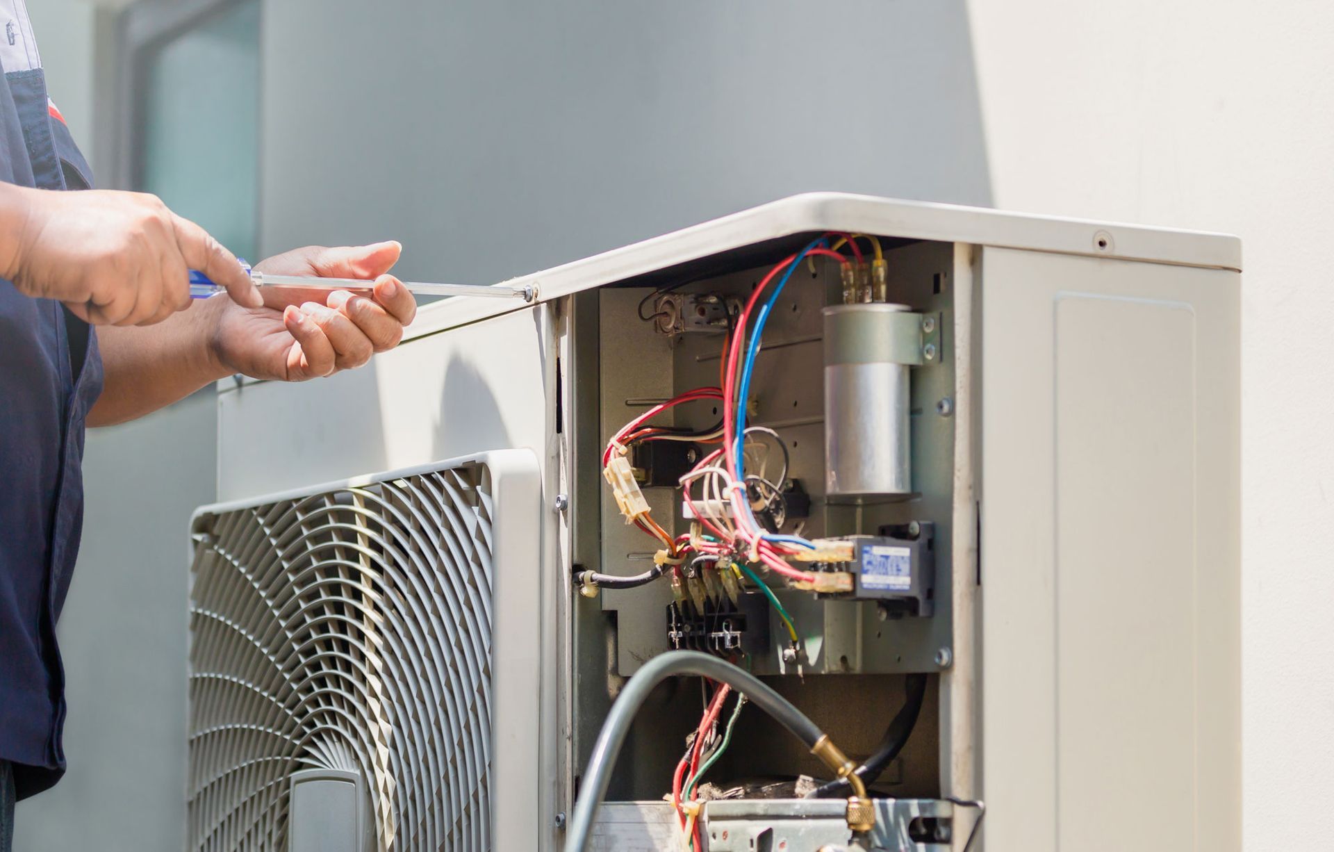 Male technician hands using a screwdriver fixing modern air conditioner