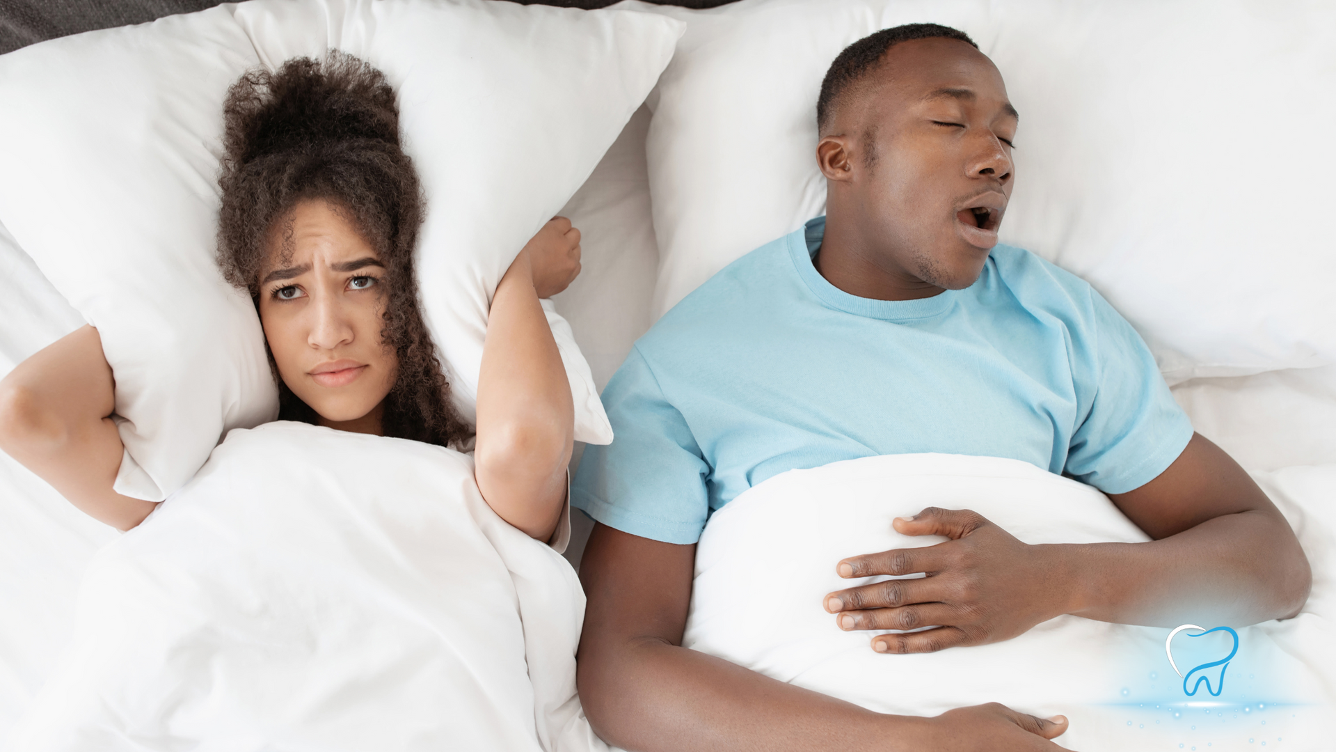 A man is snoring while a woman covers her ears in bed.
