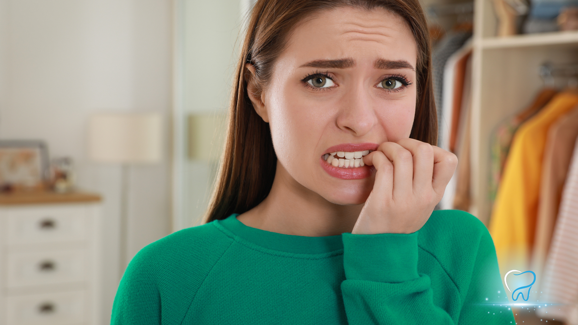A woman in a green sweater is biting her nails.
