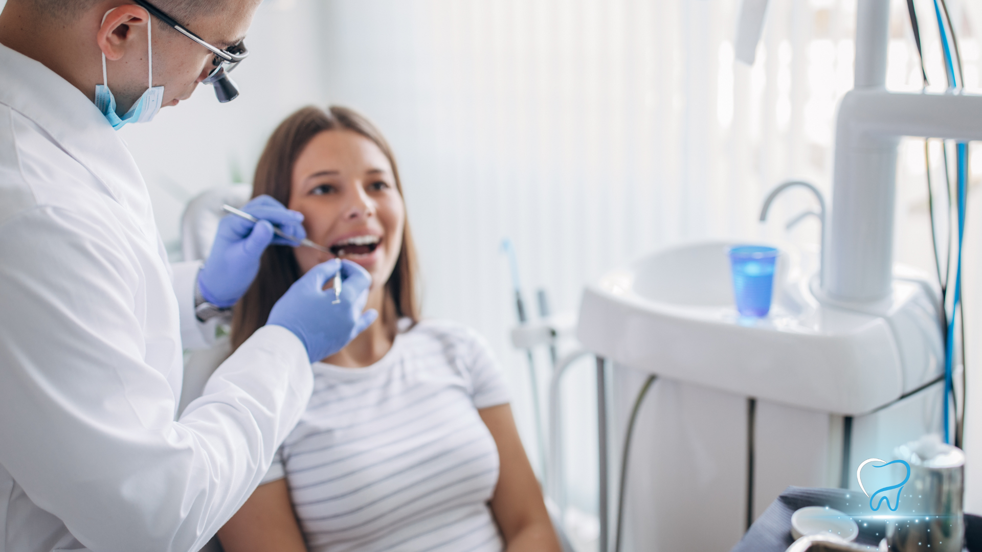 A woman is sitting in a dental chair while a dentist examines her teeth.