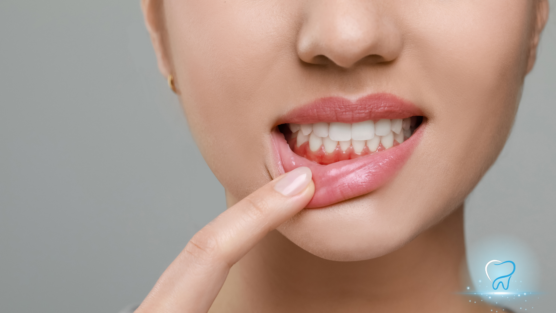 A close up of a woman 's mouth with her finger pointing to her teeth.