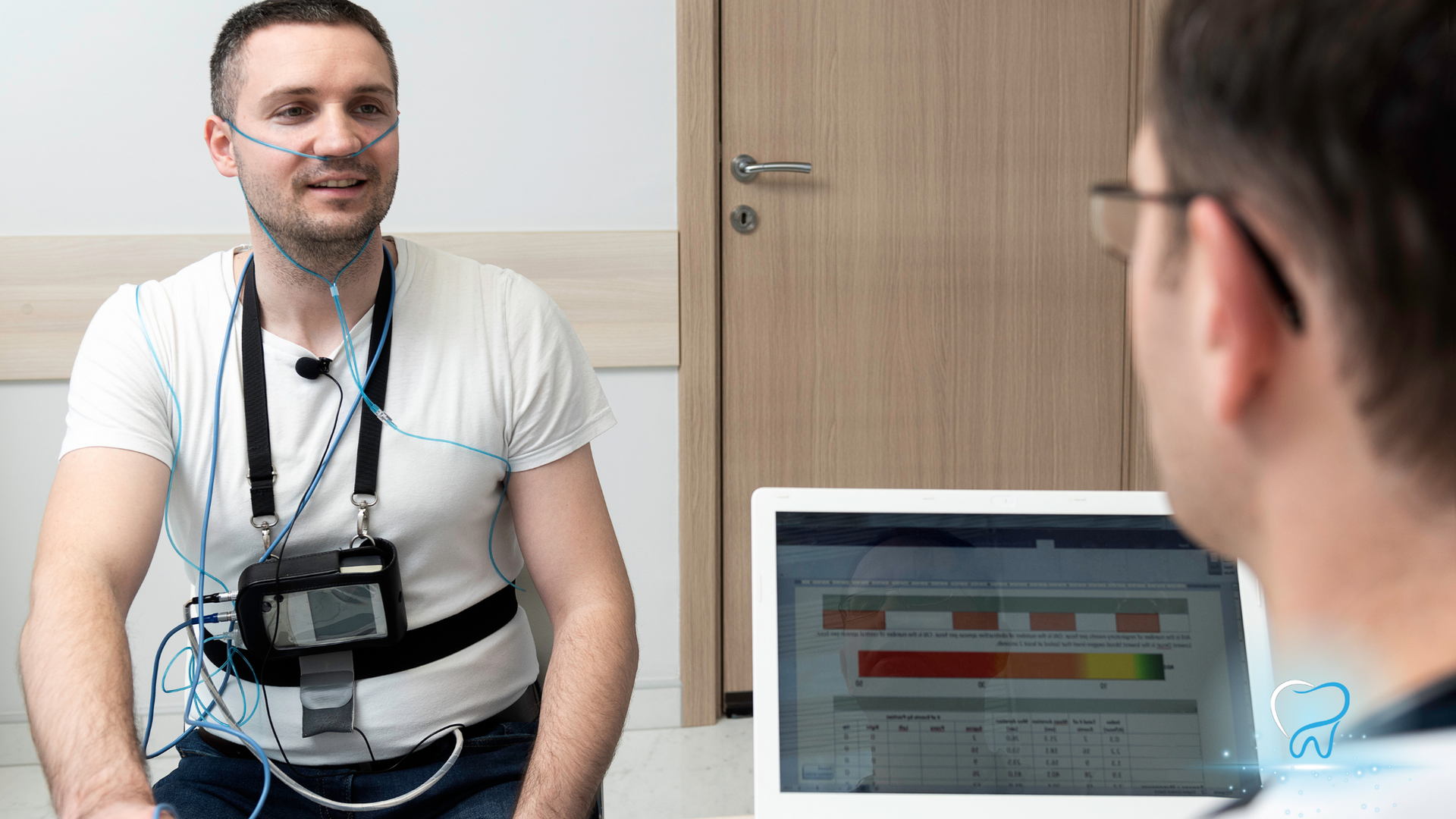 A man is sitting in front of a laptop computer while being examined by a doctor.