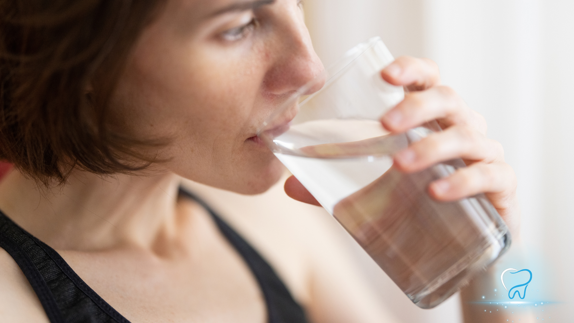 Woman drinks water from a clear glass, indoors.