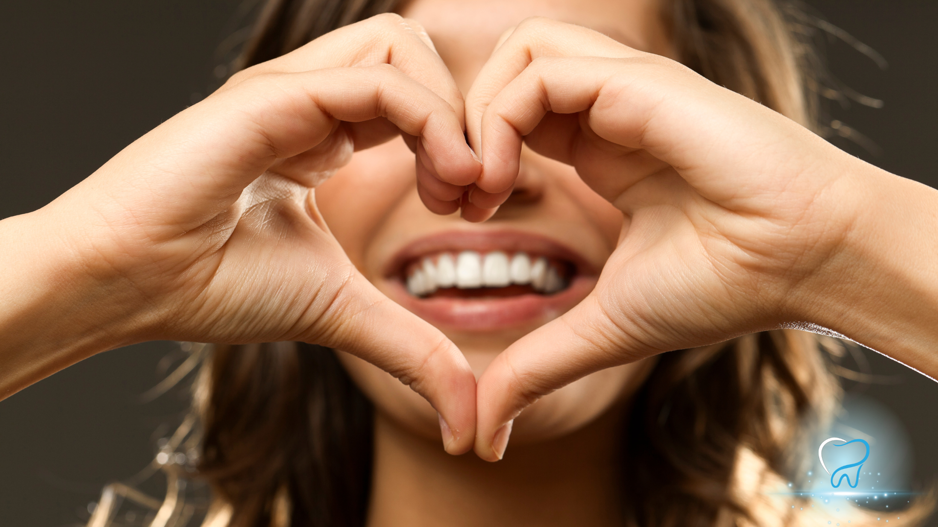 Woman forms heart shape with hands, smiling, showing white teeth.