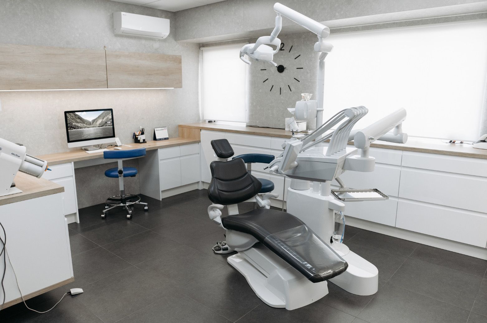 Dental office interior with dental chair, equipment, and a computer workstation.