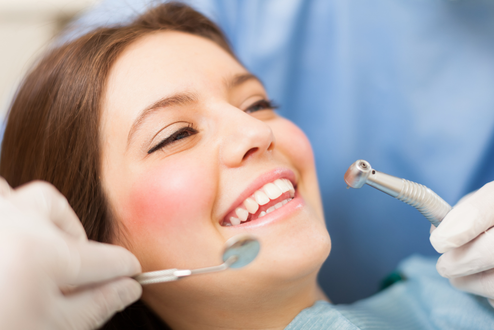 Smiling patient at dentist with dental tools near her mouth