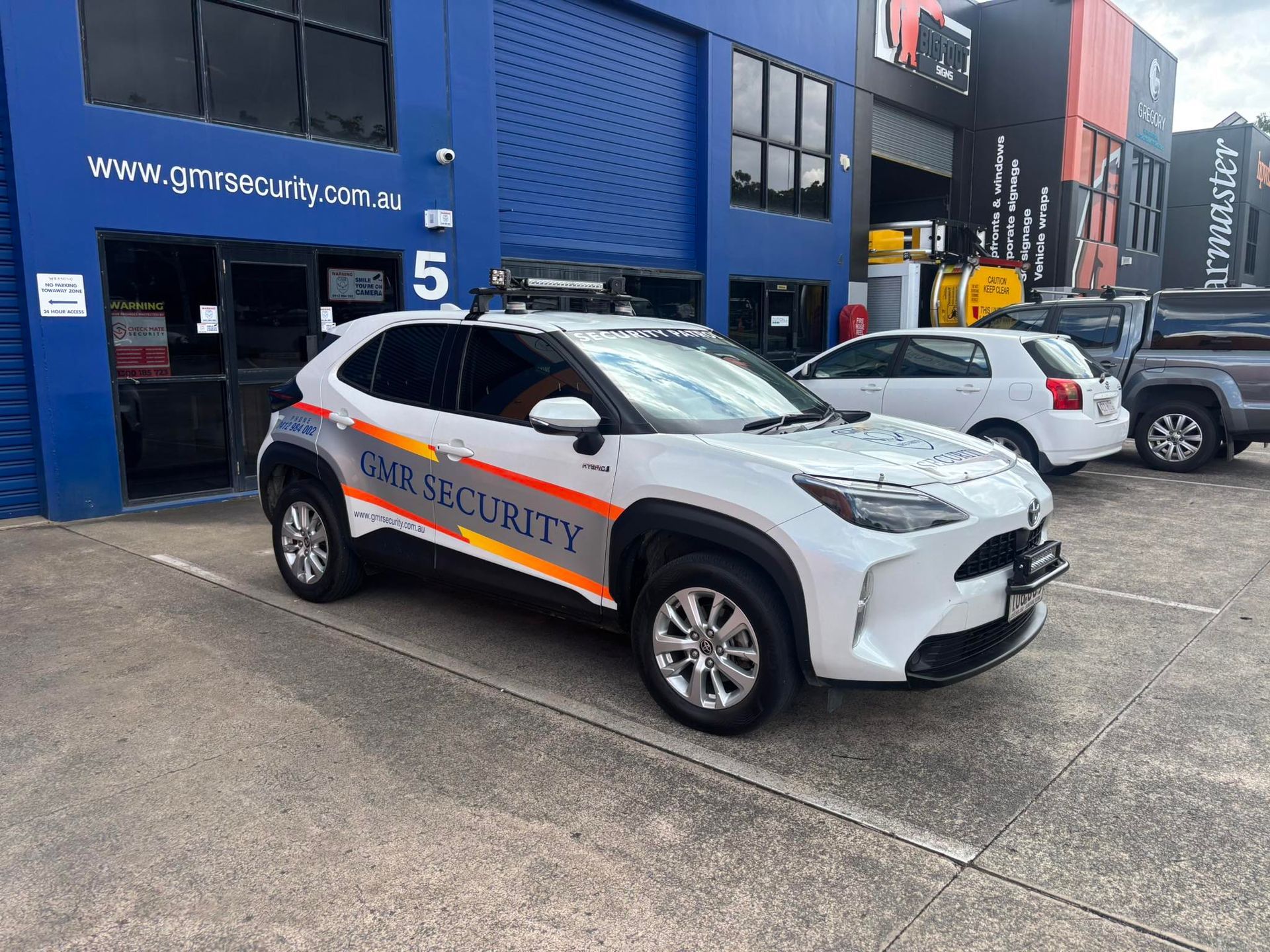 White security vehicle parked in front of a blue building. 