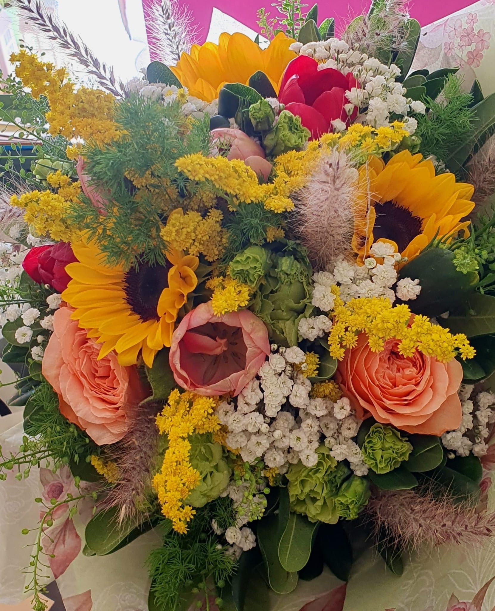 Bouquet di girasoli, rose, gypsophila e altri fiori dai colori vivaci.