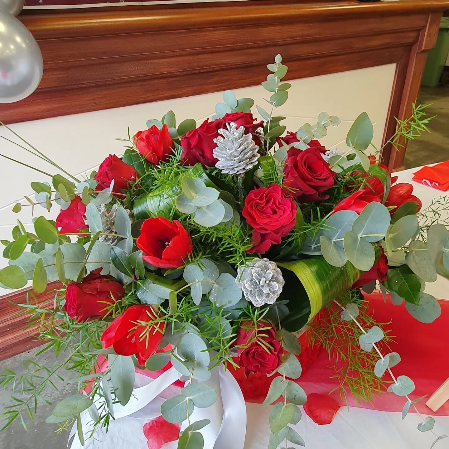 Bouquet di rose rosse e tulipani con decorazioni argentate e foglie di eucalipto.