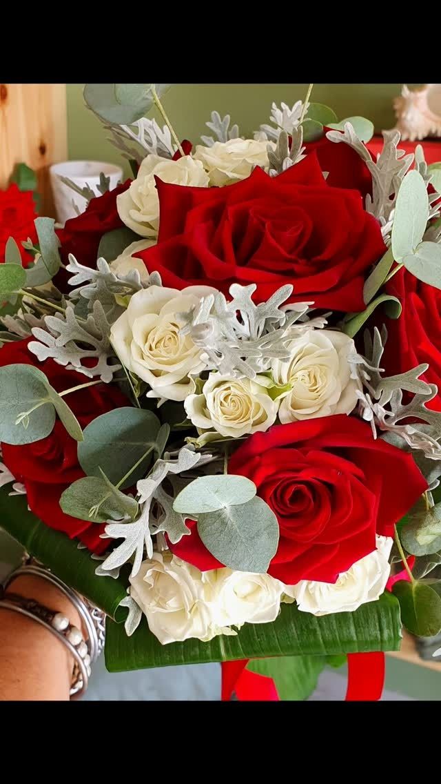 Bouquet di rose rosse e bianche con fogliame verde e argento.