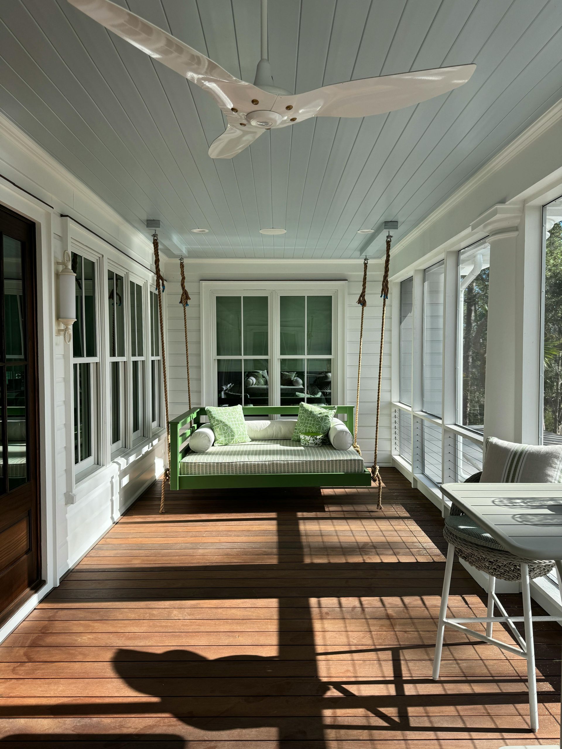 A porch with a swing and a ceiling fan