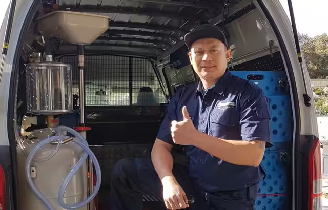 A mechanic in the back of a van giving a thumbs up.