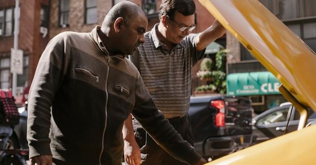 Two men are looking under the hood of a car.