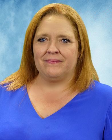 A woman with red hair and blue eyes is wearing a blue shirt.