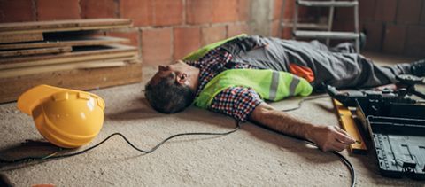 A construction worker is laying on the floor after a fall.