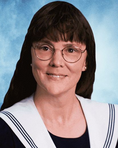 A woman wearing glasses and a sailor collar smiles for the camera