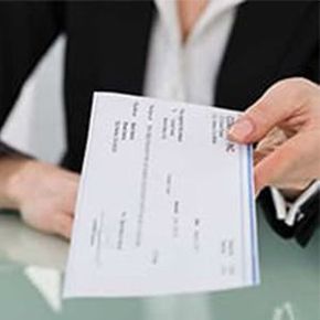 A person is holding a check in their hand.