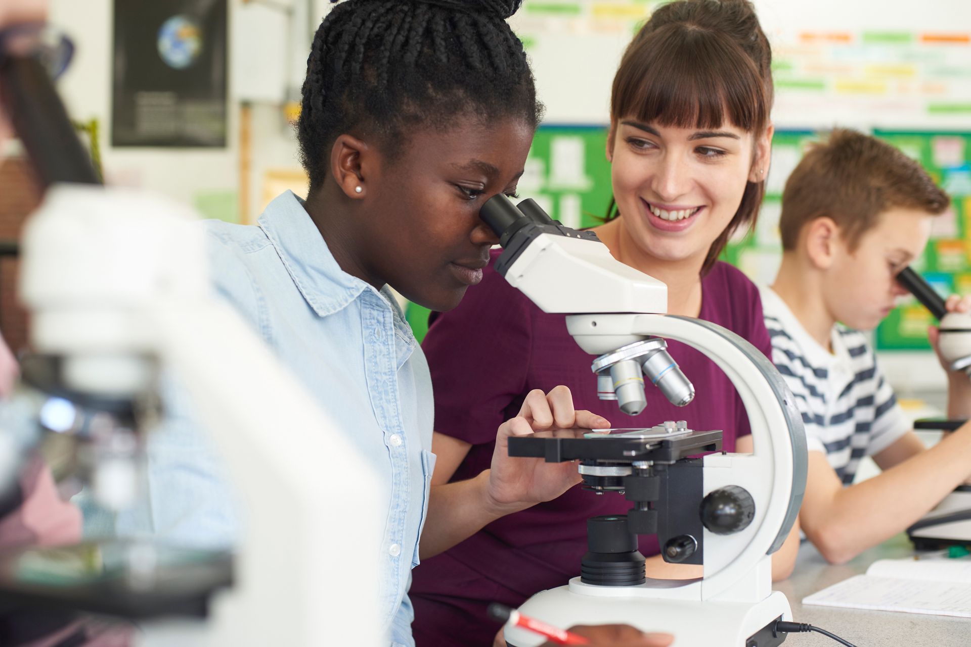 A group of students are looking through a microscope in a classroom.