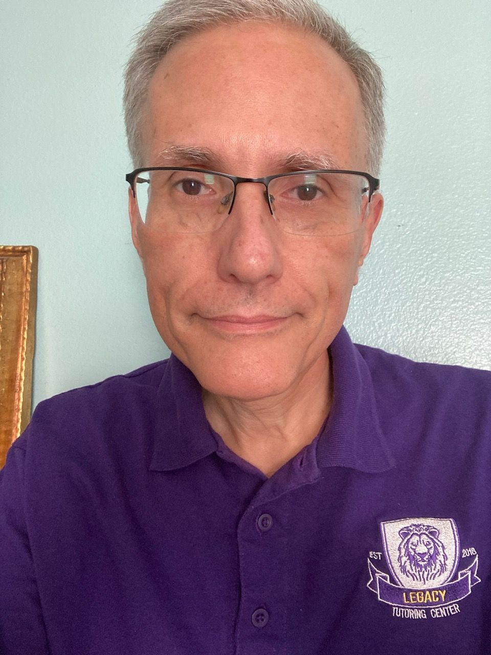 A man wearing glasses and a purple shirt is smiling for the camera.
